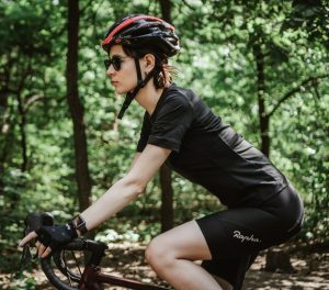 woman wearing a bike helmet while biking down the road