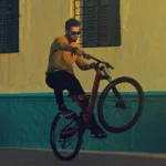 doing a wheelie on a mountain bike while wearing sunglasses