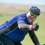 Guy giving a thumbs up while cycling with cycling glasses and a bike helmet on